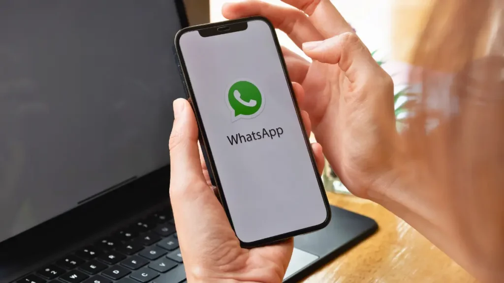 Pessoa segurando um smartphone com WhatsApp Business aberto na tela.